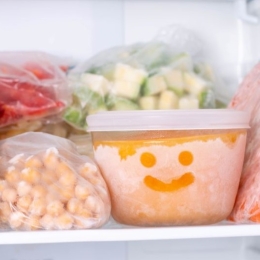 Frozen vegetables in a freezer. A bowl of frozen food with a smiley face drawn in the frost