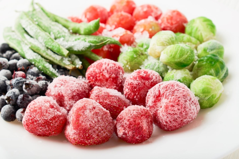 White plate with frozen food strawberries, brussels sprouts, green beans